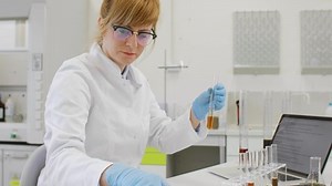 Close up of chemical scientists working with hemp CBD and CBDa oil in laboratory. She is using erlenmeyer flasks. Cannabis pharmaceutical healthcare concept.