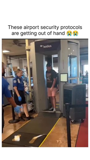 @trendeymemes on Instagram: "The video takes place at a standard airport security screening area. In the background, you can see a large Leidos body scanner, which is the high-tech machine passengers usually stand inside with their arms raised. There are several TSA (Transportation Security Administration) officers in their blue uniforms and blue nitrile gloves, managing the flow of passengers. ​Key Events ​The "Protocol": As a male traveler in a grey t-shirt and pink shorts exits the body scann