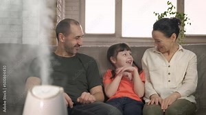 Humidifier works by family. A smart humidifier smile and relax on the sofa in the clean room.