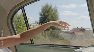 Close-up of the bride's hand sticking out the window of a retro car driving through the countryside. Inside view. Slow motion