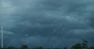 Time lapse of beautiful storm clouds moving in the sky over a residence on a cloudy day. Cell towers in the foreground.