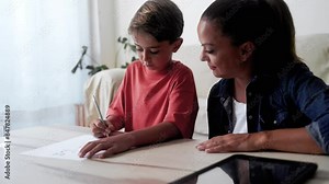Mother and son doing homework for elementary school at home. Parent help child boy with education project
