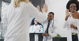 Attractive doctors medical people greeting each other with high five after right get decision during video conference with female colleague. Medicine concept.