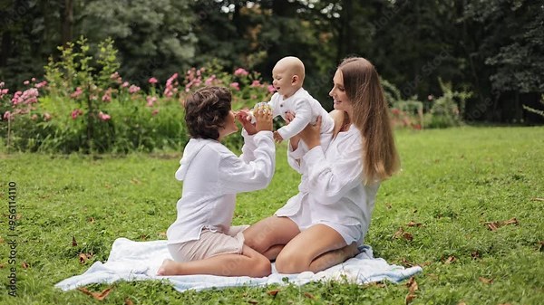 Happy family playing together in the park with their baby. Love and laughter.