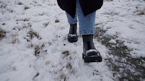 Feet of a woman walking in snow wearing winter shoes. Front view.