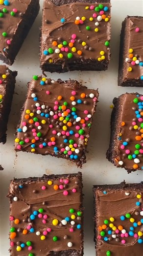 Cosmic Brownies are easy to make, customizable, and your next favorite chocolate dessert. Try them! 1 cup granulated sugar ⅓ cup light brown sugar, tightly packed 10 tbsp unsalted butter, melted ¾ cup cocoa powder 1 tsp vanilla extract 2 eggs 1 egg yolk ½ cup gluten free flour 1 tbsp tapioca flour 1 cup chocolate frosting ¼ cup rainbow sprinkles | Organically Addison