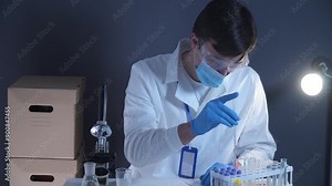 Scientist working with blood sample in laboratory. Lab analyst analyzes a blood slide. Doctor or pathologist drops a humans red blood on glass plate. Biological material to identify the virus.