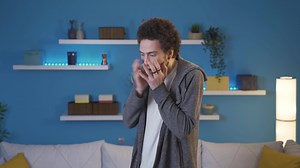 Young man having a nervous breakdown at home alone. Young man is freaking out with anger standing on the collar in the living room.