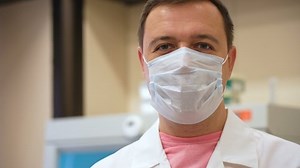 Scientist waving hello. Positive smiling researcher in laboratory looking at camera and waving right hand showing greeting. Medical man doctor salute look at camera and welcome presentation in room