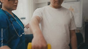 Female doctor assisting senior man to lift dumbbell, physiotherapy after injury