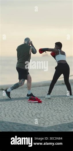Young black woman with red boxing gloves practicing punches with her personal trainer near the sea Stock Video Footage - Alamy