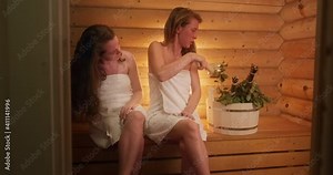Women in sauna. Two young women relax in a hot wooden sauna