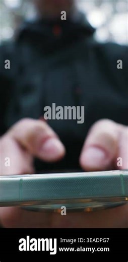 Person types on a green smartphone screen focusing on the macro detail of hands in a blurred outdoor forest. Concept of mobile communication and digital lifestyle connectivity Stock Video Footage - Alamy