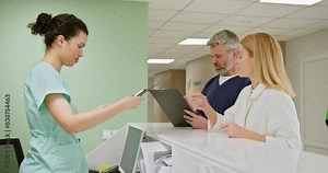 Medical professionals reviewing patient information at the hospital reception desk. Healthcare workers collaborating on patient care in a medical facility. Medical Staff Discussing Patient Records