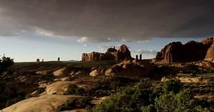 Arches National Park, Moab Utah, USA. Dramatic landscape wide shot with cars and RVs moving on curving roads in the distance.