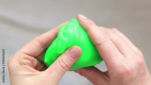 The girl kneads green slime. Female hands stretching bright green slime close-up, top view. Anti-stress toy for relaxation. A fun sensory activity. Toy store concept