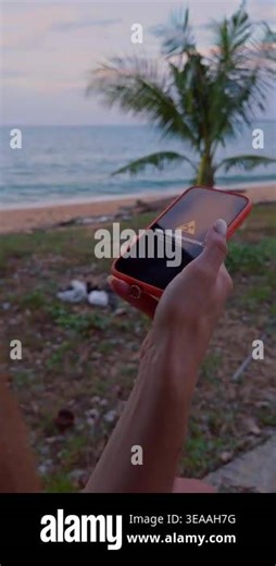Vertical video. Woman Holding Smartphone on Tropical Beach Showing Nuclear Emergency Warning With Radiation Symbol on Screen. Global Catastrophe Risk and Civil Defense Preparedness Stock Video Footage - Alamy