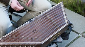 A musician plays a wooden string musical instrument by hitting it with hammers. A man plays the cymbals. Traditional musical instrument of the peoples of Eastern Europe