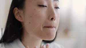 Lips care. Young pretty asian lady applying pampering balm on lips with finger at home, slow motion, empty space