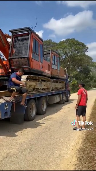 Man Walks Alongside Hitachi Excavator on Rural Road