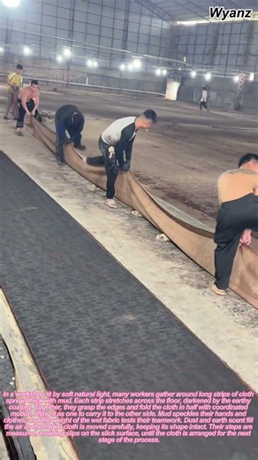 workers folding long muddy cloth in traditional fabric process | daily craft routine