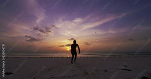 Muscular african capoeira acrobatic athlete is performing tricks on a desert sea water with splash on a sunset. Concept: healthy lifestyle, diet, wellbeing, fitness, proper nutrition, love for sports