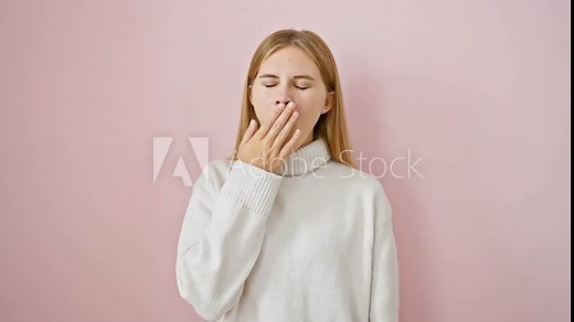 Beautiful blonde girl yawning in tiredness, covering mouth with hand, over pink isolated background. bored female expressing sleepiness, standing in bored exhaustion.