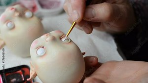 Master puppeteer draws eyes for dolls. Made the doll's eye with a brush and paint.