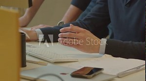 Hands of man sitting behind keyboard while a co-worker leans on the desk in support