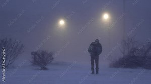 Homeless Man Walks Through Snowy Blizzard with Streetlights in the Background