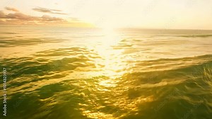 The golden sunrise reflects off gentle ocean waves creating a shimmering and tranquil scene. The sky and sea merge in shades of gold and light orange bathing the horizon in warmth.