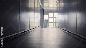 View from inside jet bridge, walking toward control panel and exit door leading to airplane boarding area. The sleek metallic design and soft lighting emphasize modern airport infrastructure