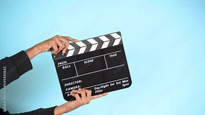 Hand is holding clapper board or clapperboard or movie slate, used in film production and cinema ,movies industry isolated over color background.