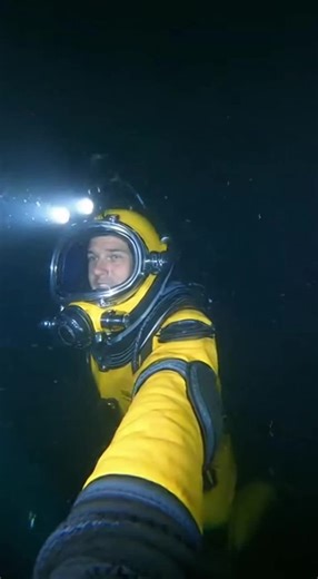 A deep-sea diver captures the moment he accidentally discovers what appears to be an ancient underwater city. His excitement is palpable as glowing ruins emerge from the darkness around him.