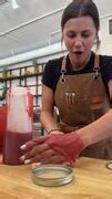 Woman spills syrup on her hand while pouring it into bottle