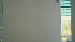 A young woman in a white satin robe entered the room and closed a door behind her, white shoes high heeled in her hand.