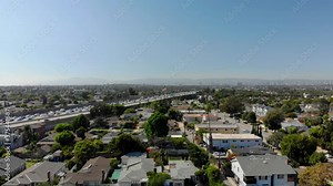 Aerial over neighborhood overlooking traffic on Interstate 405 with mountains in the background, the San Diego freeway, bright, sunny day, in Los Angeles, California, USA - drone shot