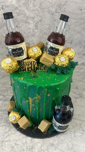 Boutique Cakes And More on Instagram: "For the Kraken rum lover 🐙🥃 Because men’s birthday cakes should be dark, rich, and slightly dangerous. Chocolate peanut butter cake stacked with peanut butter Swiss meringue buttercream, salted caramel sauciness between every layer, and topped with Kraken rum, Ferrero Rochers, and homemade caramel fudge. Not a dainty slice. A statement cake. 💣🍫 #krakencake #krakenrum #mensbirthdaycake #boozycake #chocolatepeanutbutter peanutbutterlover saltedcaramel fer