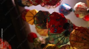 Various silk lanterns and decorations that hang in a shop are filmed in closeup from below. Vibrant atmosphere of handmade ornaments store in Vietnam representing an important symbol in Asian culture.