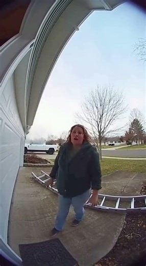 Ring camera footage of a woman catching a falling ladder as a worker loses balanc