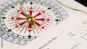 Pendulum for tarot and a astrological circle next to horoscope data sheet form and pen on the dark wooden background