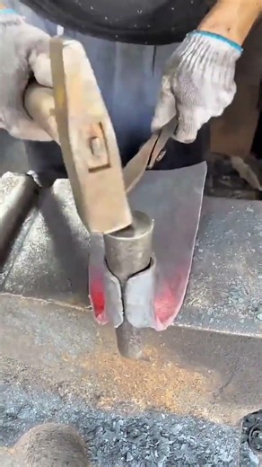 sharpening a steel axe blade using a professional electric bench grinder machine in a workshop