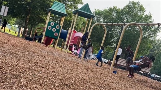 Two kids fall back-to-back while playing on the swings at the playground
