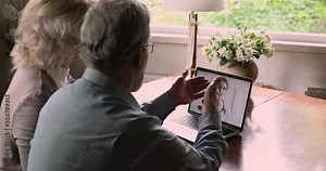 Rear view aged couple having online consultation with doctor by video call, pc screen over spouses shoulder. General practitioner consults gives advice to older people remotely use modern tech concept