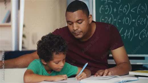 African American dad helps son with math equations, doing homework together