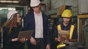 Three heavy industry business engineering in hardhats discuss information on laptop computer while standing indoors welding manufacturing industrial for check and control automated programming Stock Video