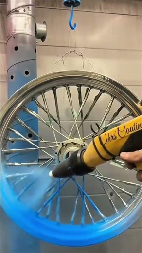 applying blue powder coating to a motorcycle wire spoke wheel rim using an electrostatic spray gun