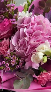 Beautiful bouquet of chamelaucium uncinatum, fresh roses, carnation, freesias, hydrangea, eucalyptus in tender pink and white colors, bouquet of flowers close up. Floral shop concept.