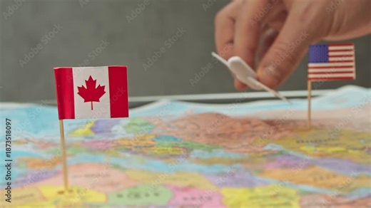 Toy airplane between United States and Canada flags over political world map, symbol cross border carriers, joint ventures and dense air traffic in Canada US market.