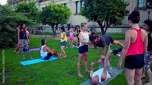 A group lesson on acroyoga master class which takes place on the lawn in the park. Slowmotion shot